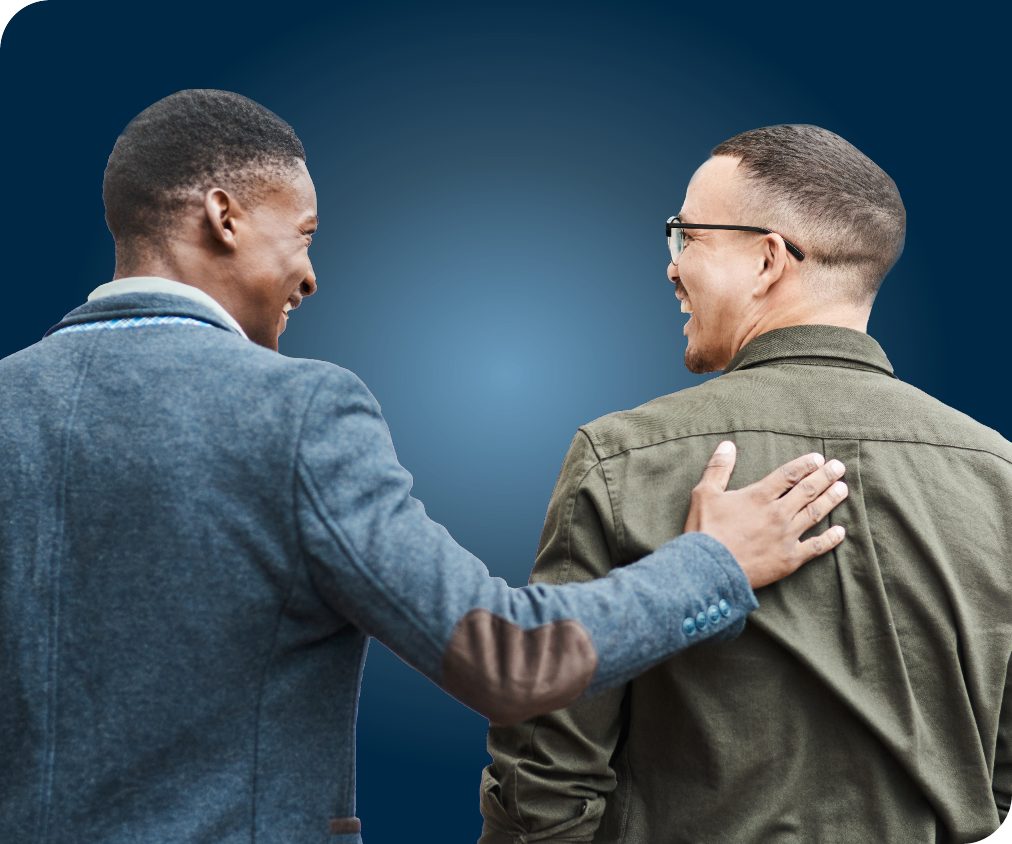 Image de dos de deux hommes se souriant l’un à l’autre, l’un tapotant le dos de l’autre